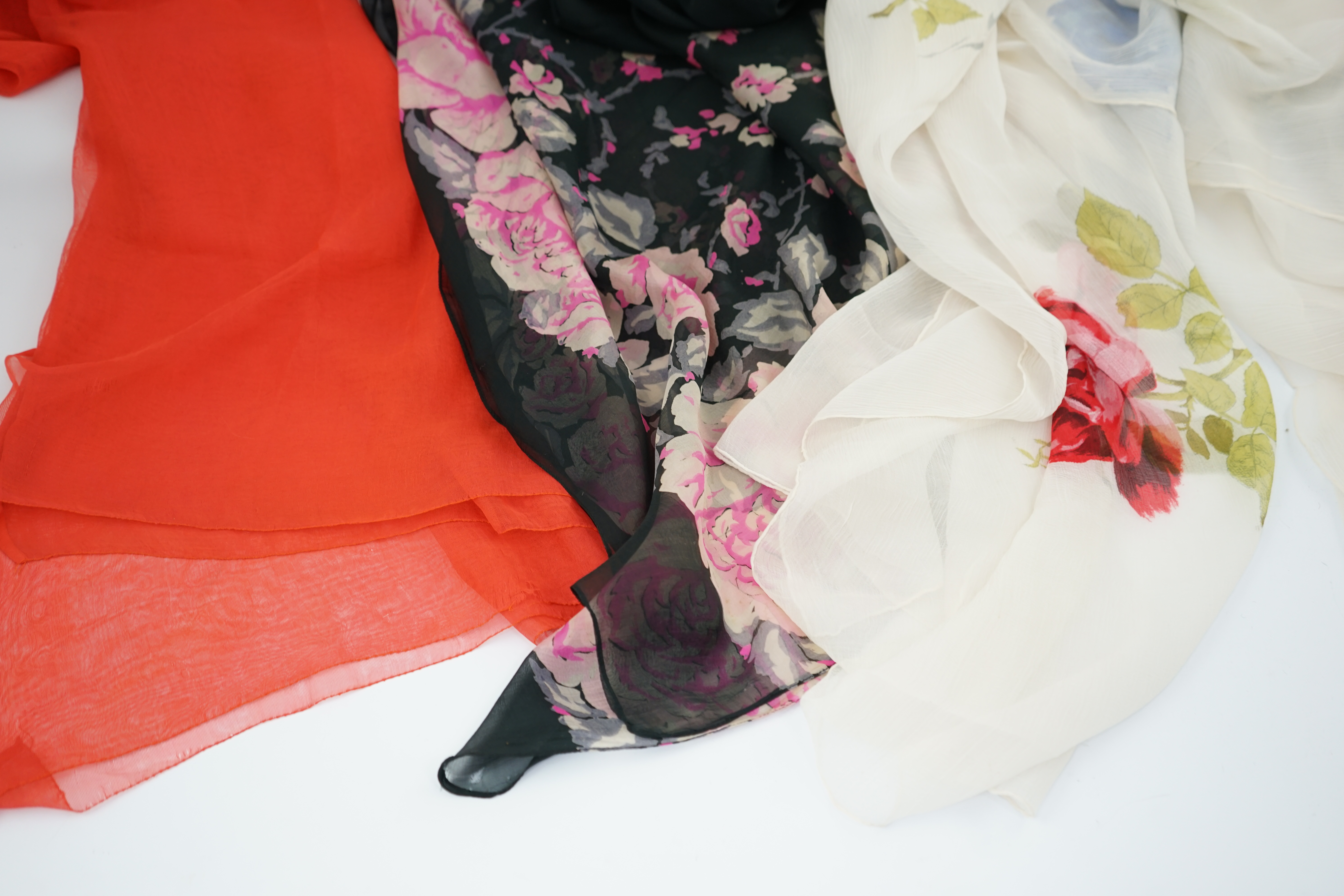 Three 1950s silk chiffon evening stoles, one cream crepe de chine designed with large red and blue single stem roses, another black silk chiffon with wide pink rose border, the other a plain coral chiffon, cream stole 18